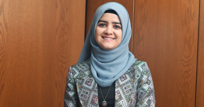 a woman wearing a blue head wrap, smiling. 