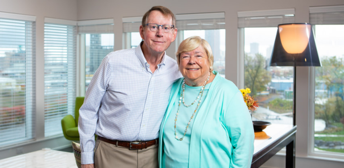 photo of two people standing in a bright room with lots of windows. 