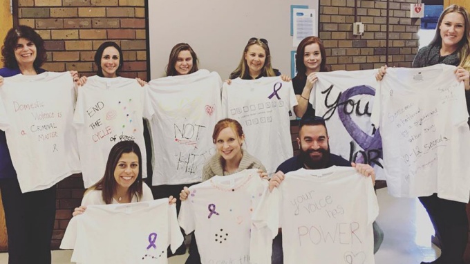 members of the domestic violence task force show off tshirts with motivational writing on it. 