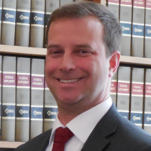 photo of Michael Pastrick standing infront of a bookshelf. 