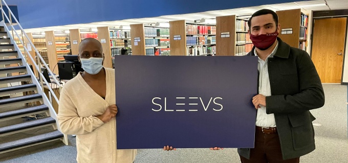 two law students hold up a sign that says Sleevs. 