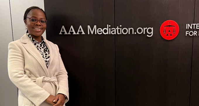 student standing next to a AAA Mediation.org sign. 