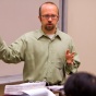 man standing in front of a whiteboard teaching a class. 