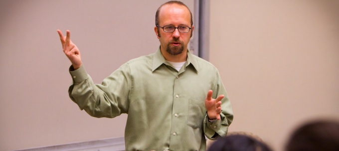 man standing in front of a whiteboard, teaching a class. 