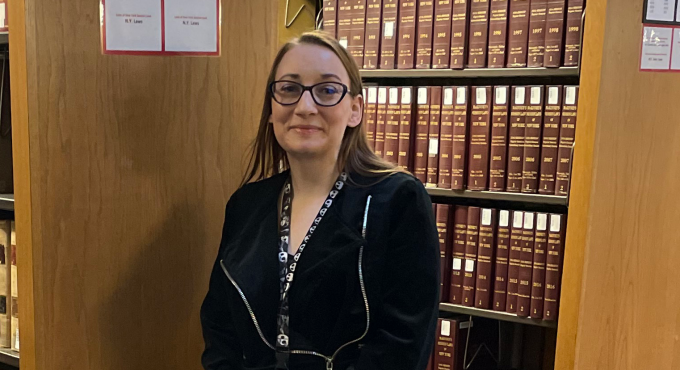 woman standing next to a bookshelf. 