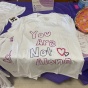 closeup photo of a white tshirt with the writing 'You are not alone' and a heart. 