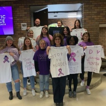 a group of people displaying white tshirts with writing on them. 