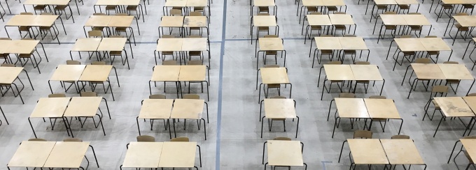 large room with many empty desks and chairs set up in several rows. 