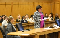 attorney in a courtroom with students observing in the audience. 
