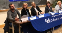 individuals sitting at a table in a classroom, leading a panel discussion. 