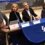 individuals sitting at a table in a classroom, leading a panel discussion. 