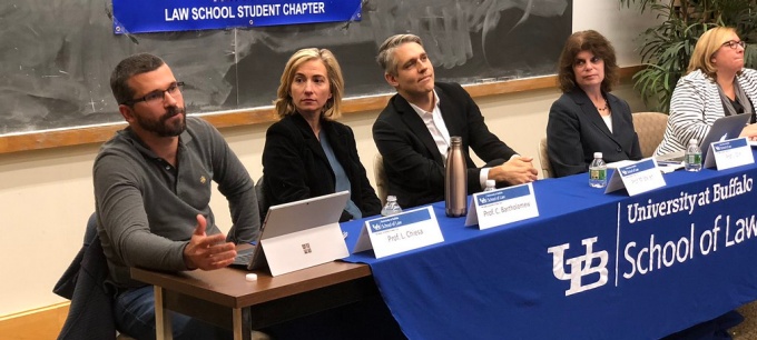 people sitting at a table leading a panel discussion. 