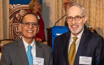 two men standing in front of a table. 