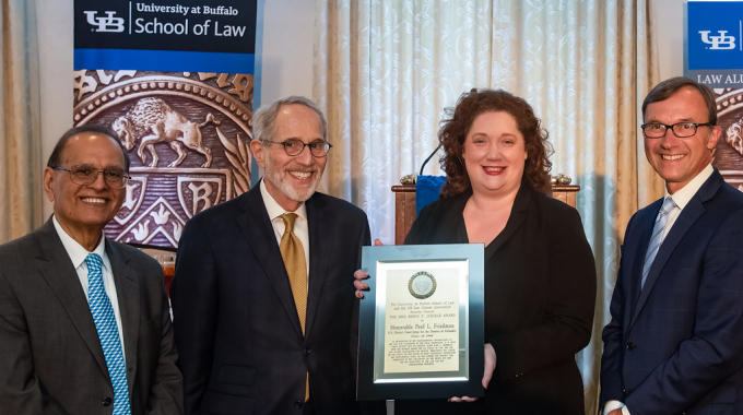 photo of four people, one holding up award plaque. 