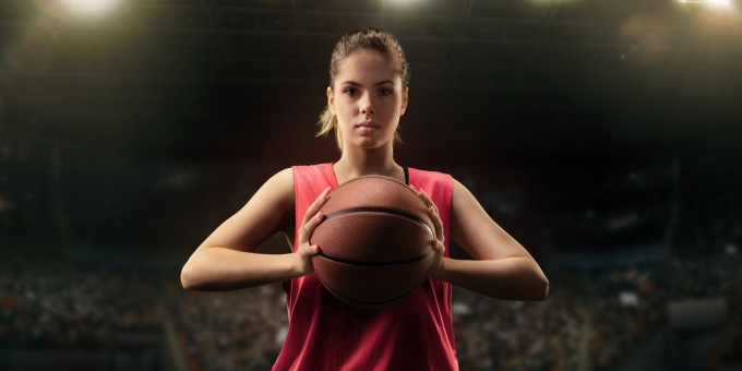 woman in an athletic stadium holding a basketball. 