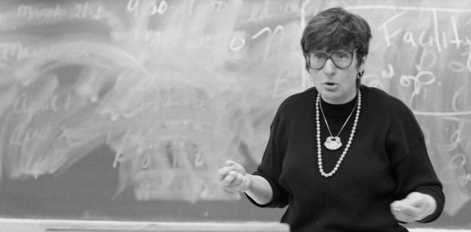 black and white photo of woman in front of a chalkboard. 