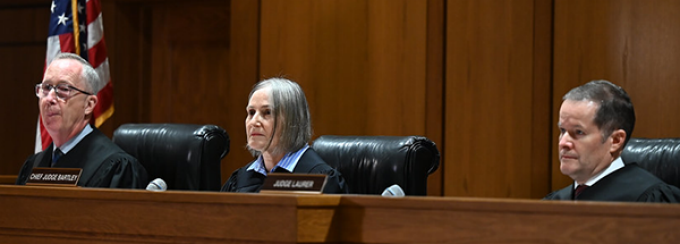 3 people siting at a judges bench. 