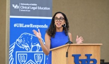 woman standing at a podium, talking. 