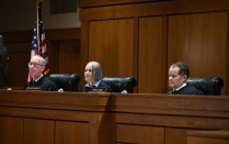 two men, one women, sitting at a judges bench. 