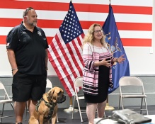 group of people with US flag, addressing a room of attendees. 