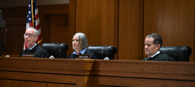 two men, one women, sitting at a judges bench. 