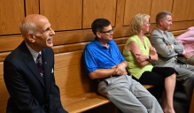 people sitting in a courtroom, observing arguments. 