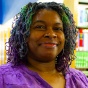 woman standing inside a library, smiling. 