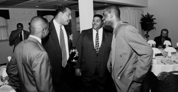 black and white photo of four men, taking. 