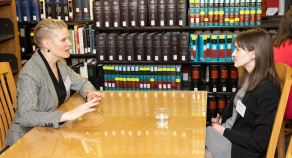two women sitting at a table in a library. 