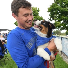 young man holding a puppy wearing a blue bandana. 