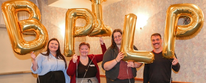 students holding up balloons that spell BPILP. 