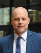 man in business suit standing outside a building. 