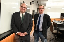 two men in a classroom, smiling. 