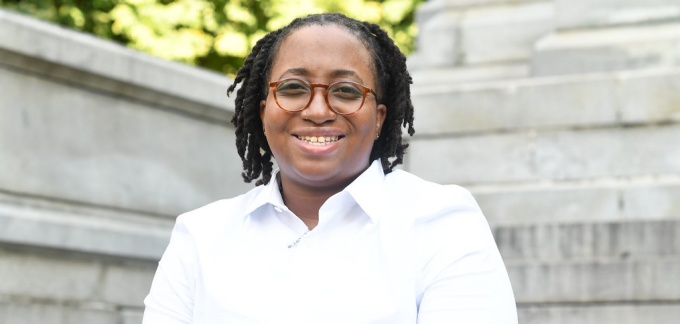 woman smiling, sitting outside of a courthouse. 