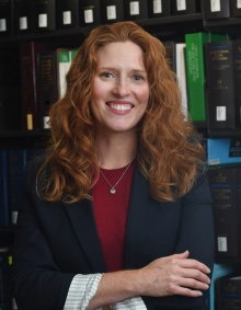 smiling woman standing in front of bookcases. 