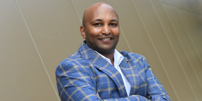 man wearing striped jacket, crossing his arms, smiling. 