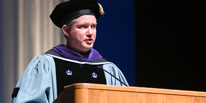 man speaking at a graduation podium. 