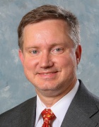 man wearing a suit, smiling for a portrait photo. 