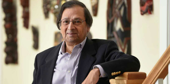 man wearing glasses standing next to a staircase. 