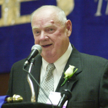 man speaking into a microphone at an event. 