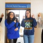 four people standing in front of a doorway, pointing at a sign that says Diversity, Equity & Belonging. 