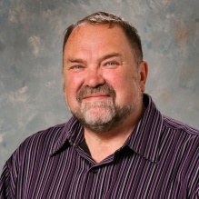 ma wearing striped shirt, smiling. 