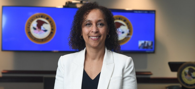 woman wearing white blazer, standing in a media room. 