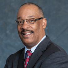 man wearing business suit, glasses, posing for a portrait photo. 