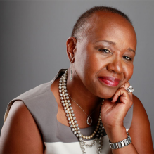 woman wearing pearl necklace, smiling. 