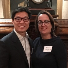 Zoom image: man and womans standing in front of a clock