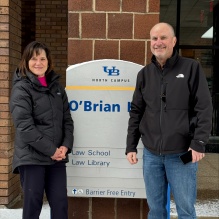 Zoom image: man and woman standing in front of a sign for O'Brian Hall