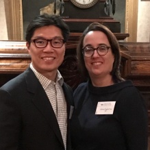 man and womans standing in front of a clock. 