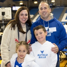 family with a boy and girl, standing inside a sports arena. 