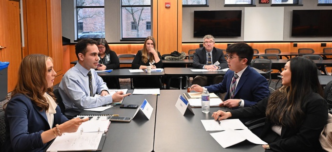 students sitting at a group of tables, facing each other, in a deep discussion. 